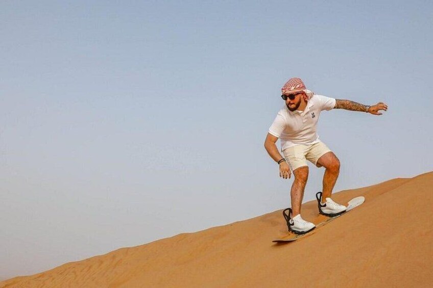 A person riding a board down a sand dune. 4