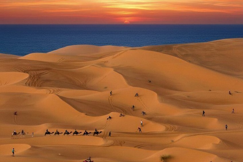 A desert landscape with sand dunes and a sunset over the ocean. 1