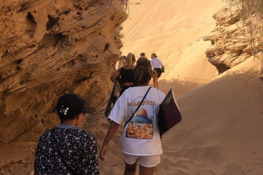 Un grupo de personas caminando por un cañón estrecho con terreno arenoso y paredes rocosas. 1