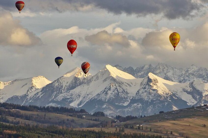 A mountainous landscape with snow-capped peaks and hot air balloons in the sky. 2