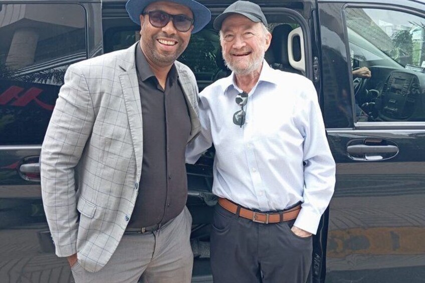 Two men standing in front of a black vehicle. 3