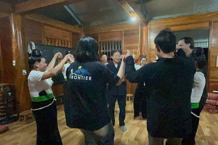 A group of people dancing in a wooden room with a blackboard and a stool. 4