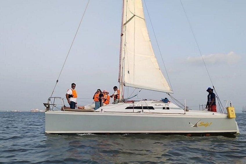 Een zeilboot met mensen aan dek, een heldere lucht en rustig water. 4