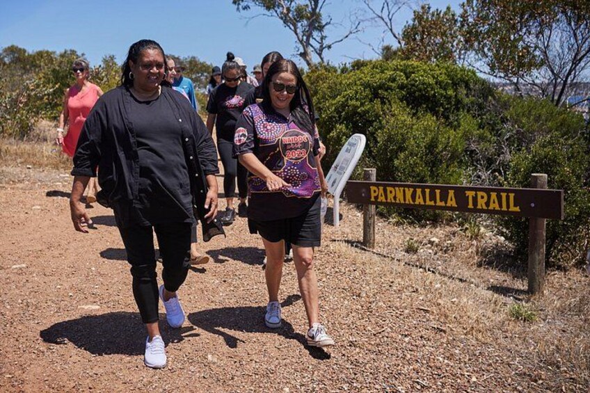 A group of people walking on a dirt path with a sign for the Parkalla Trail. 4