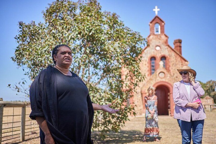 A person in a black dress standing in front of a church with a cross on top. 1