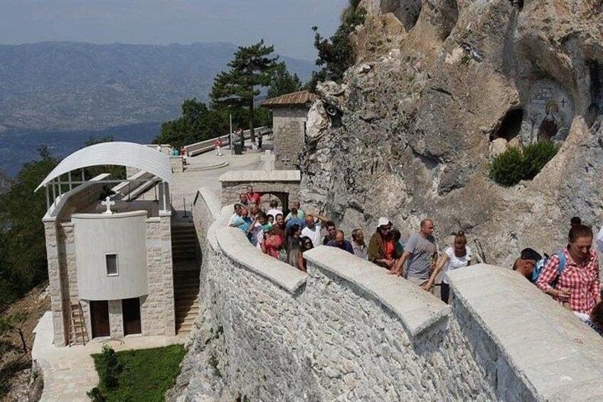 A rocky cliff with a stone building and a curved staircase. 2