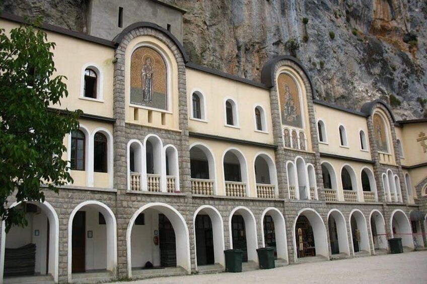 A building with multiple arched windows and balconies, set against a rocky cliff backdrop. 3