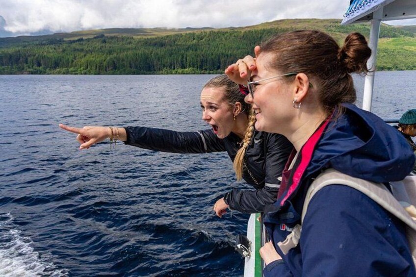 Two people on a boat pointing towards the water. 4