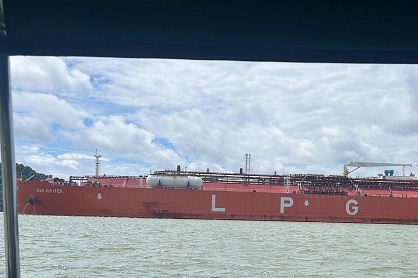 A large red cargo ship with the letters 'LPG' on its side, docked at a port with a cloudy sky in the background. 2