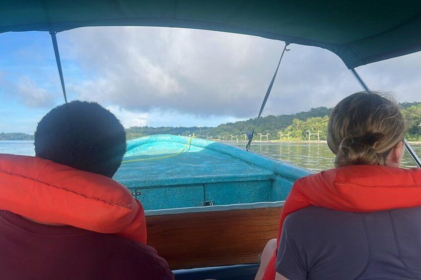 Deux personnes à bord d’un bateau, portant des gilets de sauvetage, observent une étendue d’eau dont les rives sont verdoyantes, sous un ciel nuageux. 5