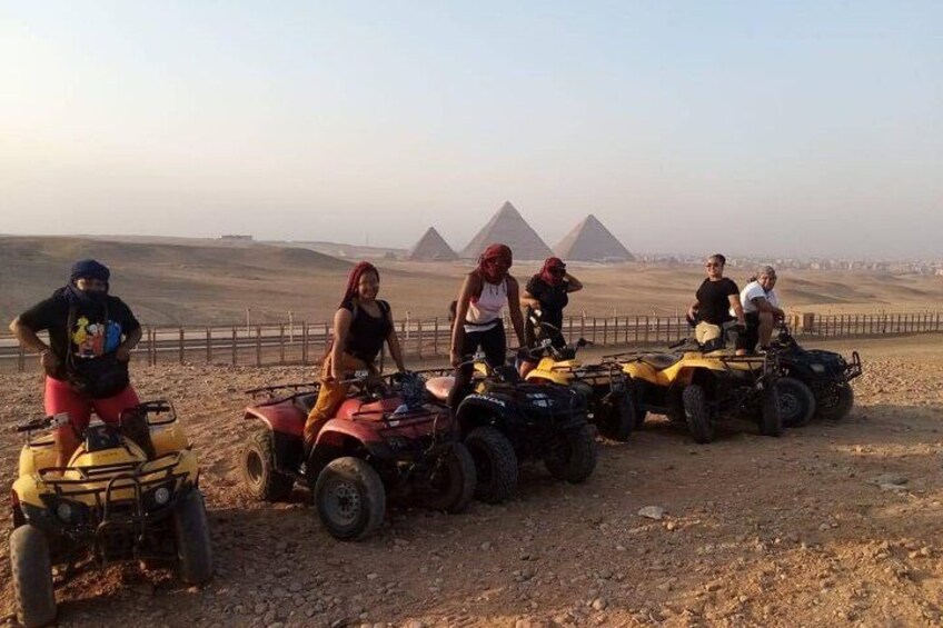 Un grupo de personas manejando vehículos todo terreno en un paisaje desértico con pirámides al fondo. 5