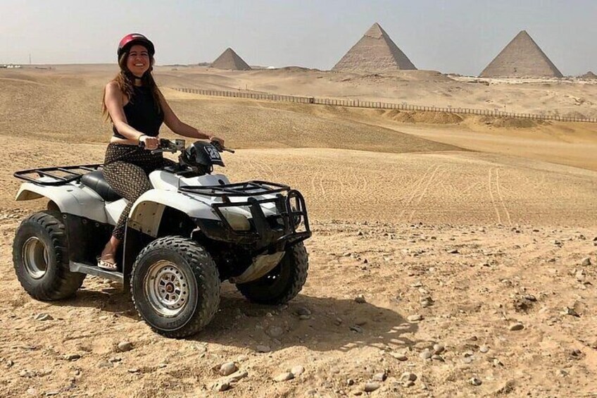 Una persona en un vehículo todo terreno en un desierto, con pirámides al fondo. 4