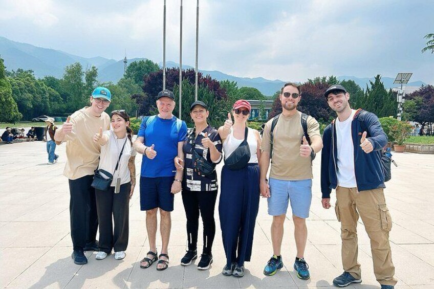 A group of people posing for a photo in an outdoor setting with a clear sky and mountains in the background. 2