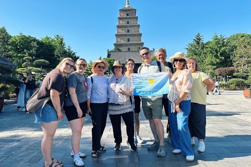 A group of people standing in front of a pagoda-like structure with a flag. 3
