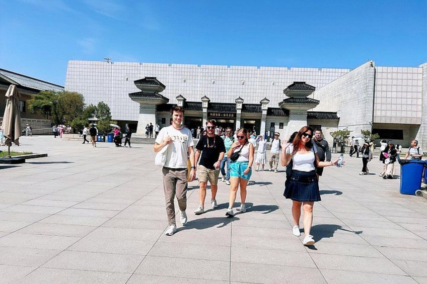 A group of people walking in a plaza with a modern building in the background. 3