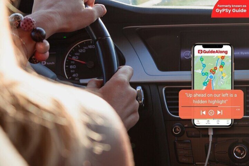 A person driving with a GPS device displaying a map and a message about a hidden highlight ahead. 1