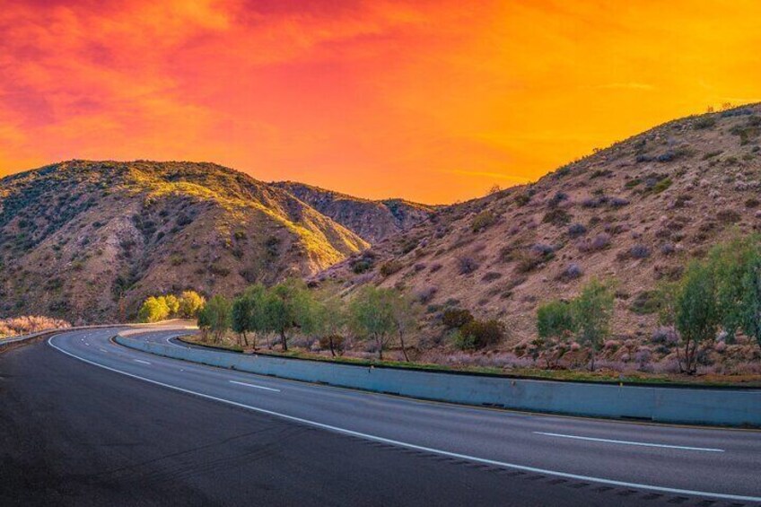 A winding road through a hilly landscape with sparse vegetation. 3