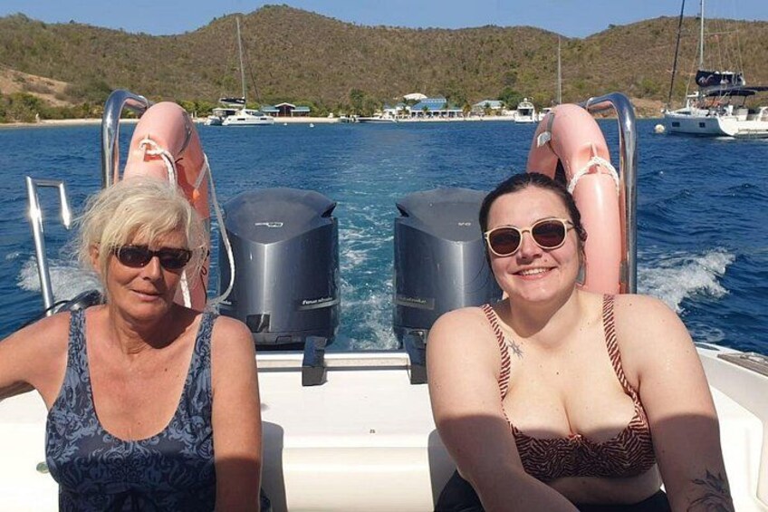 Two people on a boat with a water body and boats in the background. 4