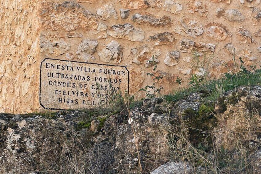 A stone wall with a sign in Spanish. 3
