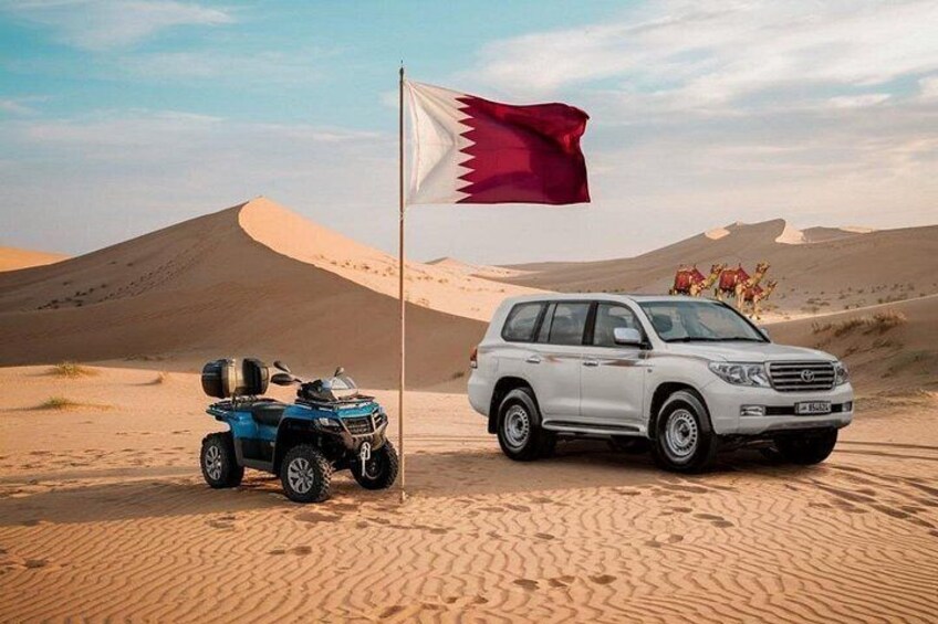 A desert landscape with sand dunes, a white SUV, and a blue ATV. 1