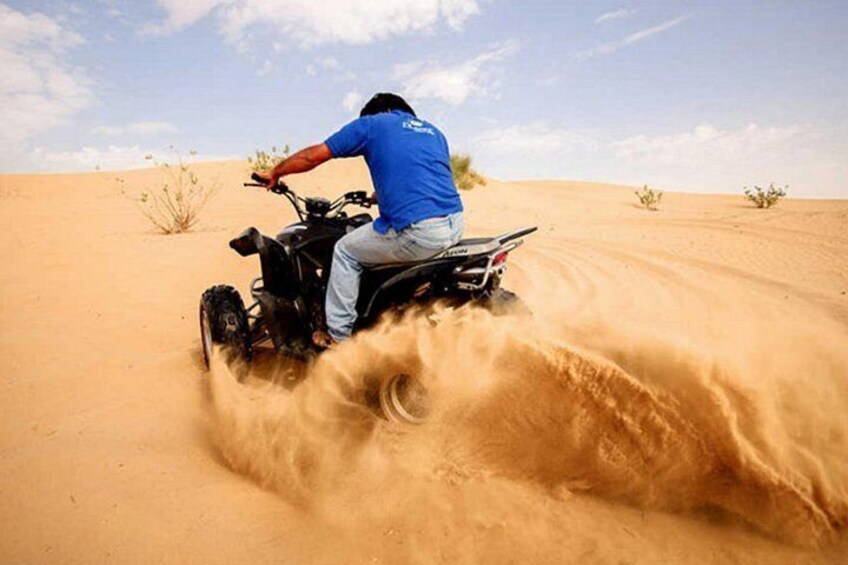 A person riding an ATV in a desert with sand dunes. 2