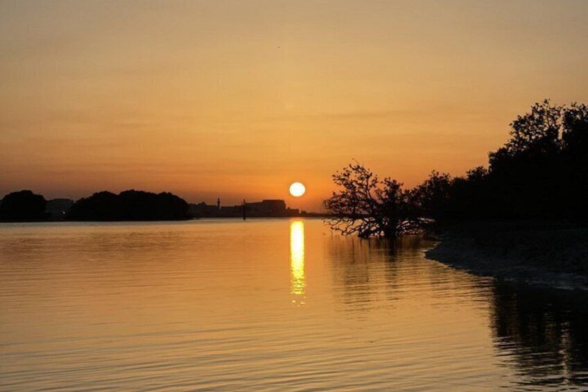 A sunset over a calm body of water with a tree silhouetted against the sky. 3