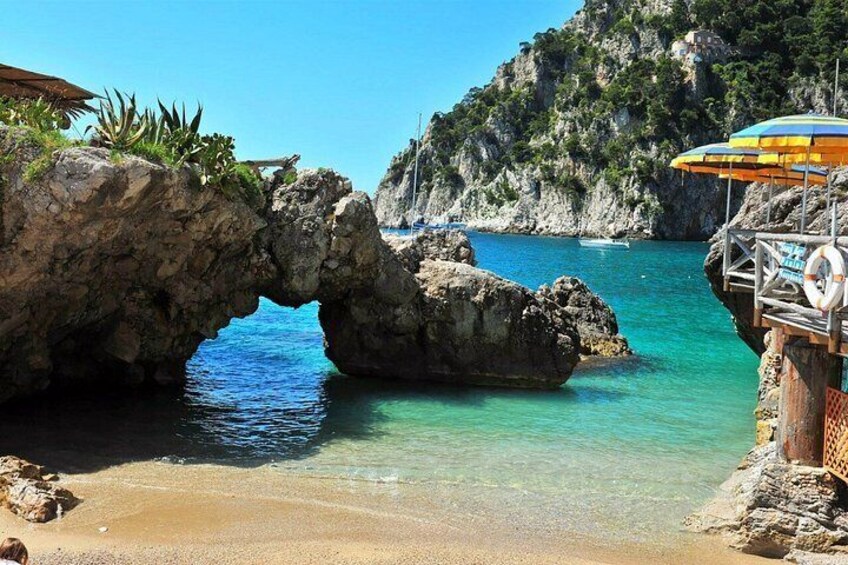 Un paisaje costero con una formación rocosa, agua turquesa cristalina y una playa. 4