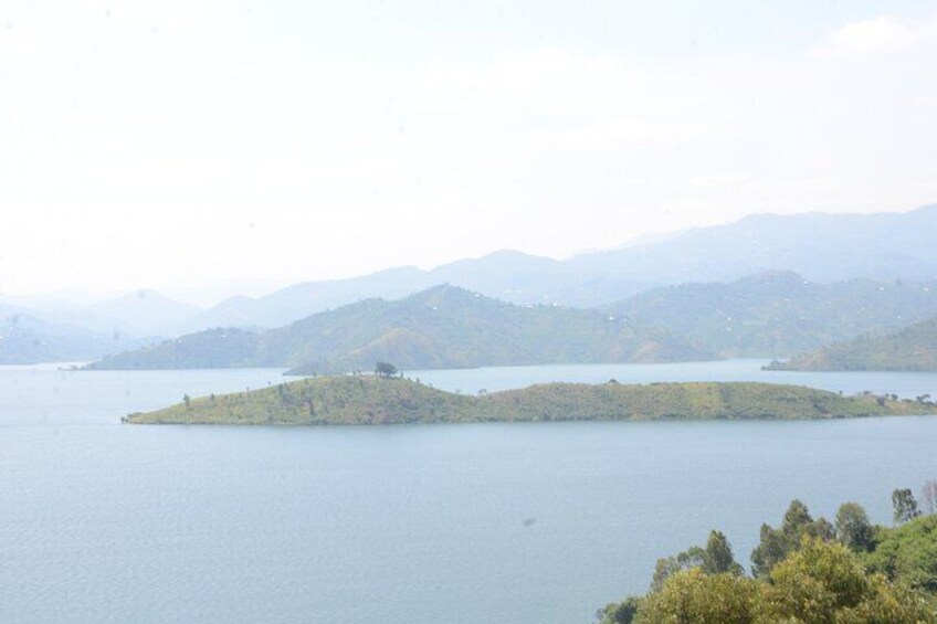 A calm lake with a small island in the center and mountains in the background. 1