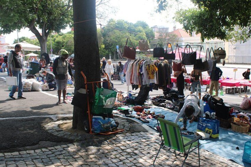 A street market with various stalls selling clothes and bags. 2