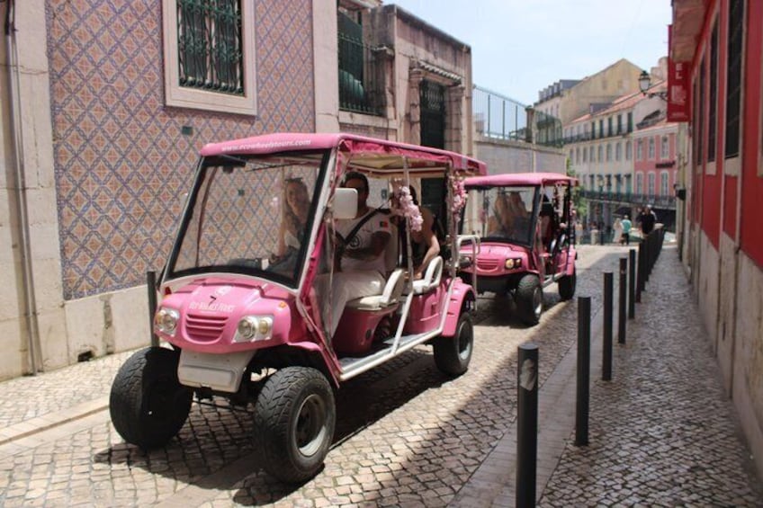 En rosa jeep på en kullerstensgata med byggnader i bakgrunden. 3
