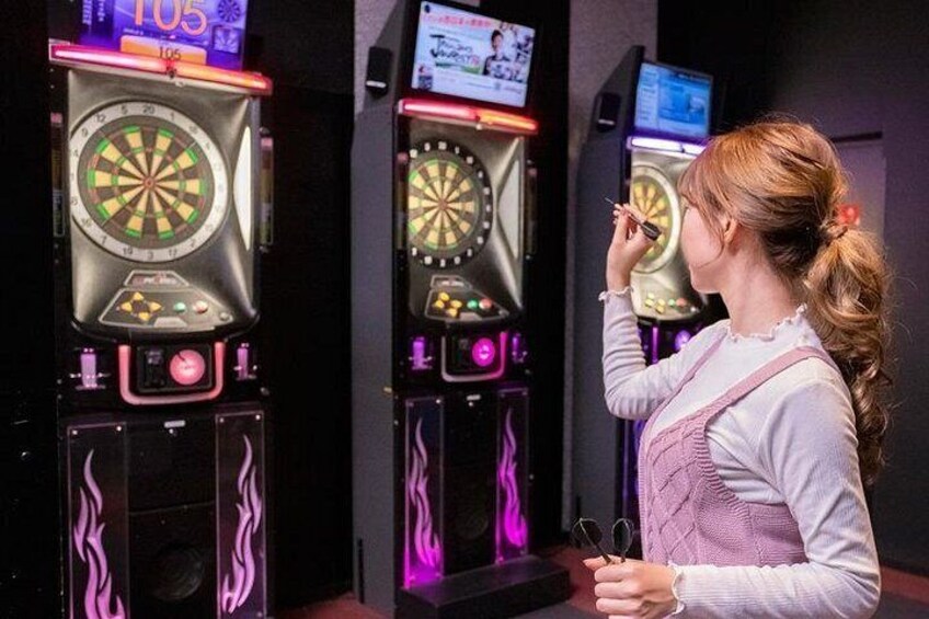 A woman playing a dart game at an arcade. 2