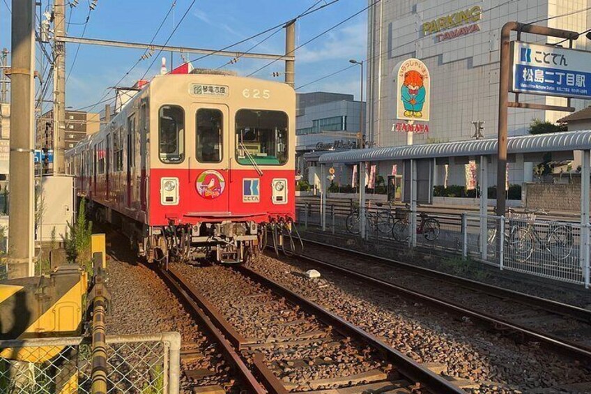 A red and white train on tracks with a building and a sign in the background. 4