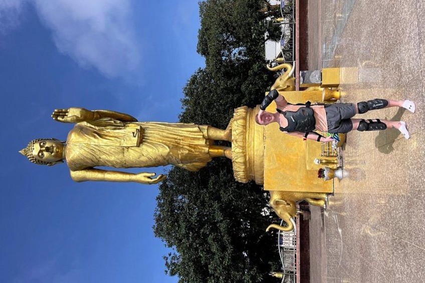 En stor, gylden statue af en siddende figur, en person foran den, og en gylden bygning med et buet tag. 4