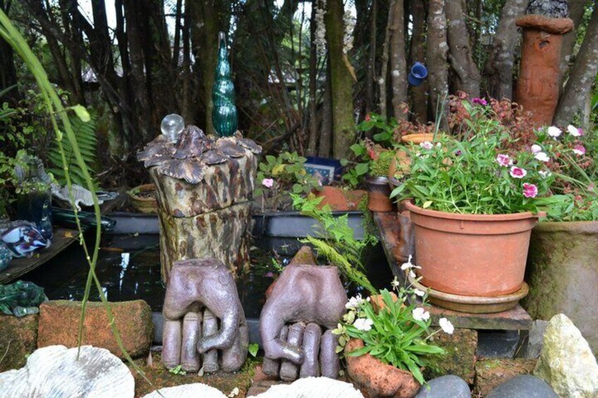 Un jardín con esculturas de piedra, plantas en macetas y una valla rústica. 4