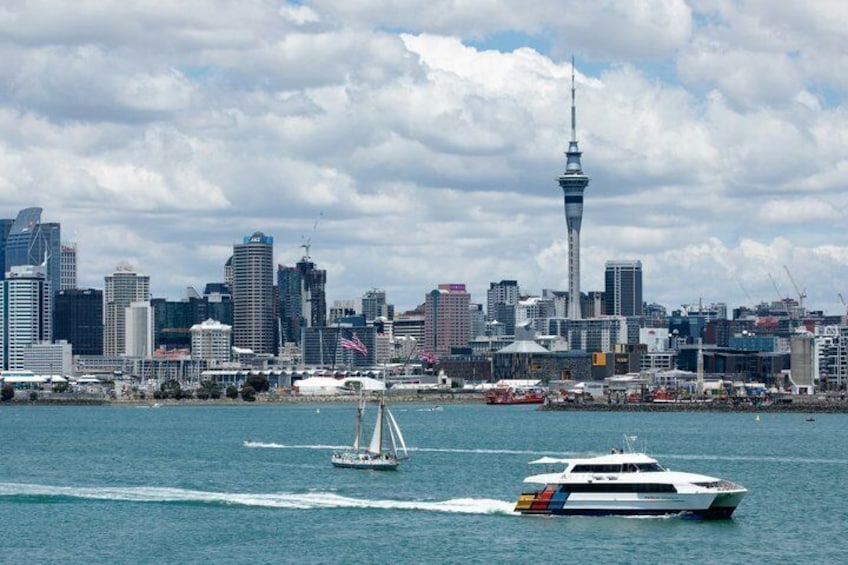 A city skyline with a prominent tower, a sailboat, and a yacht on the water. 5