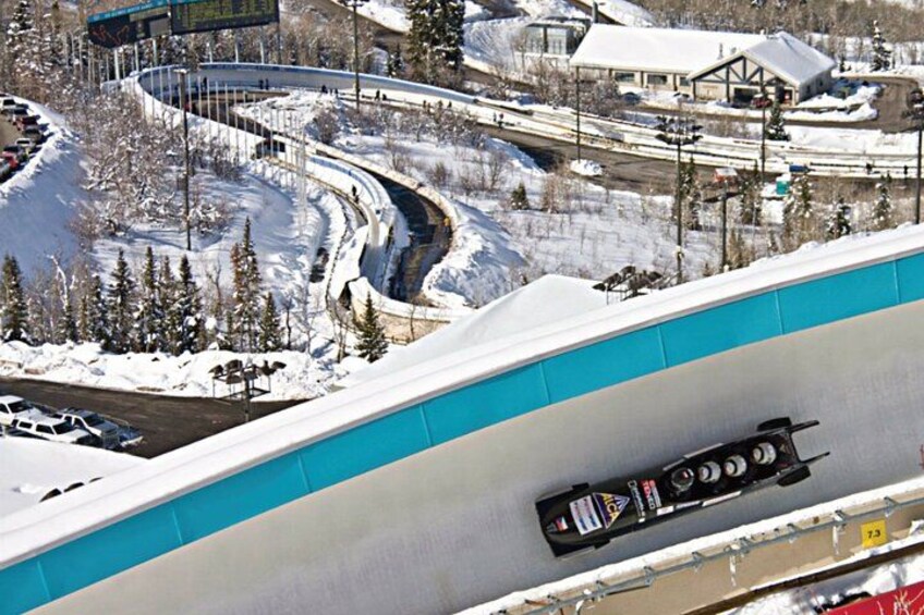 A ski lift with a blue and white track, a snow-covered mountain, and a snowmobile on the track. 2