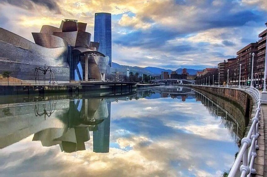 A modern architectural structure with a reflective water surface, a bridge, and a cityscape in the background. 2