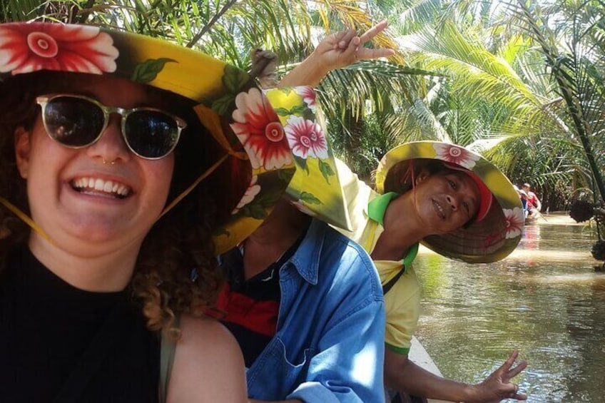 People wearing hats with floral patterns, standing in a water body surrounded by greenery. 1