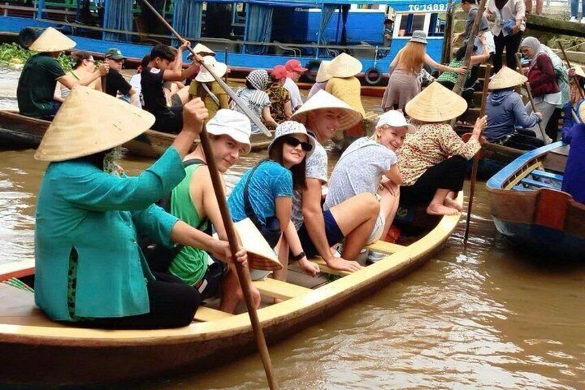 People in a boat, wearing conical hats, paddling through a body of water. 4