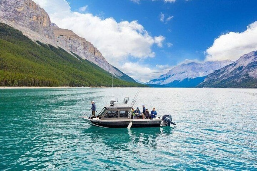 A boat on a calm lake with mountains in the background. 1
