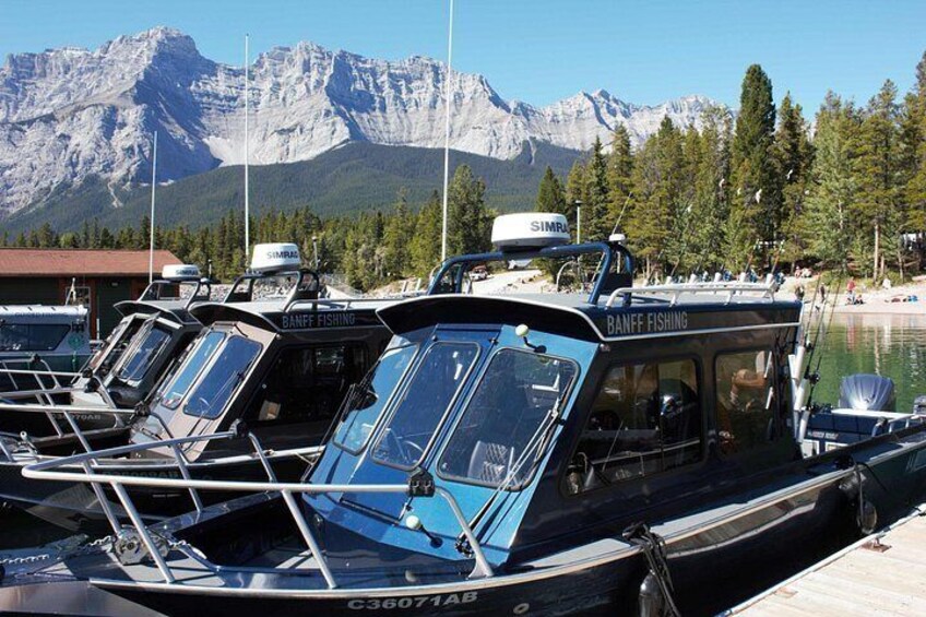 A row of boats docked at a marina with mountains in the background. 3