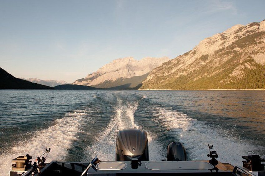 Un bote navegando por un lago con montañas al fondo. 4