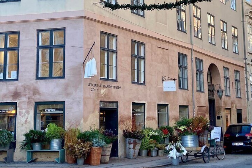 A building with a sign reading "Store Strandstredde 20-2" and potted plants in front. 1