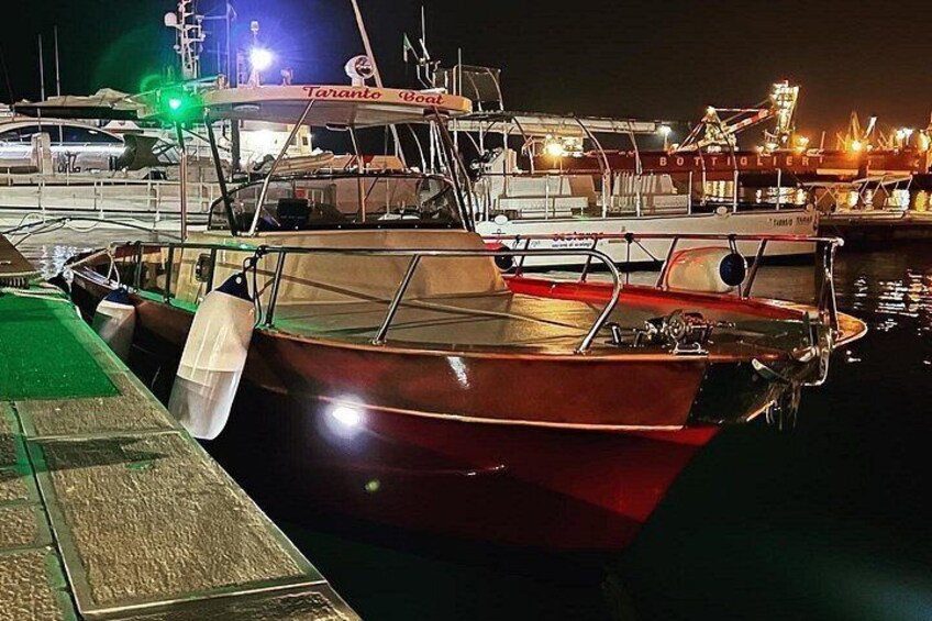 Un bote rojo amarrado en un puerto deportivo, con otros botes y un edificio al fondo. 5