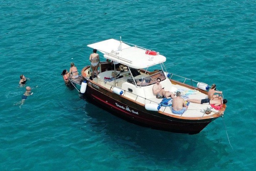 A boat with people on board, surrounded by clear blue water. 1