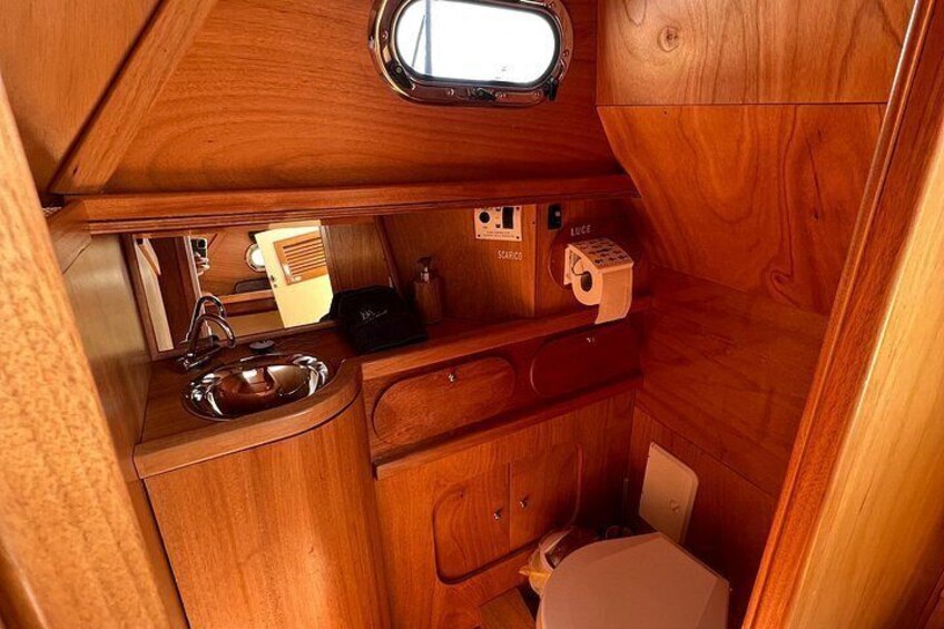Una kitchenette de madera compacta con un lavamanos, una pequeña estufa y un inodoro. 3