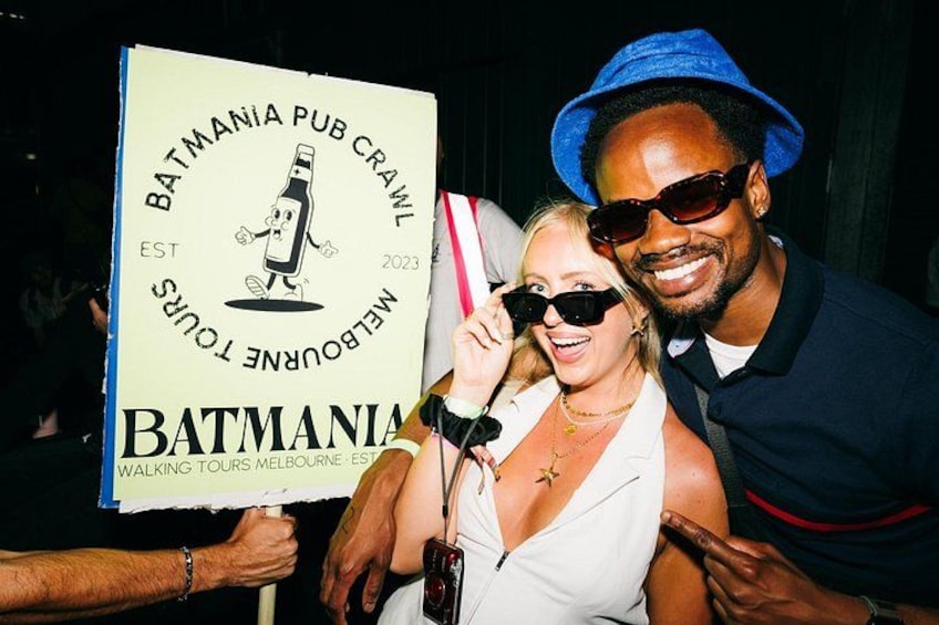 A person holding a sign with text and a graphic of a bottle. 1