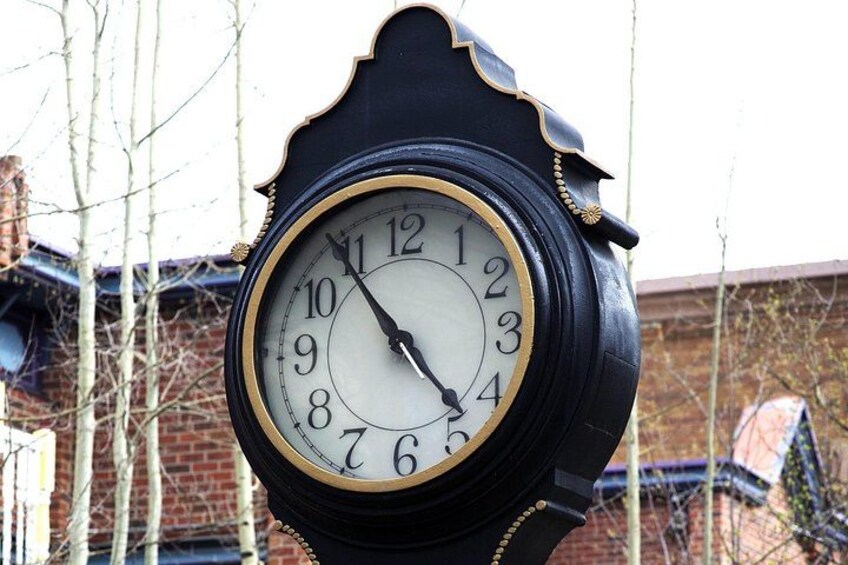 A black clock with gold trim and numbers, mounted on a post. 4