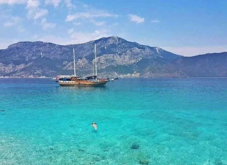 A boat on turquoise water with a mountain in the background. 5