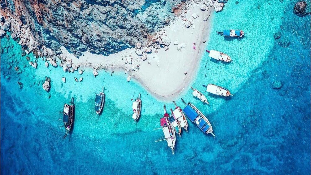 An aerial view of a beach with boats anchored in clear turquoise waters. 2